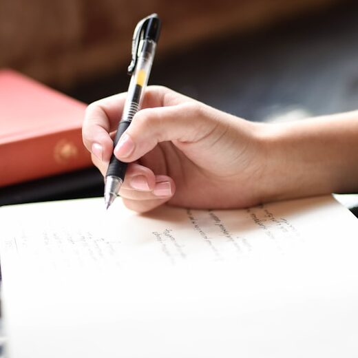 a person writing on a piece of paper with a pen
